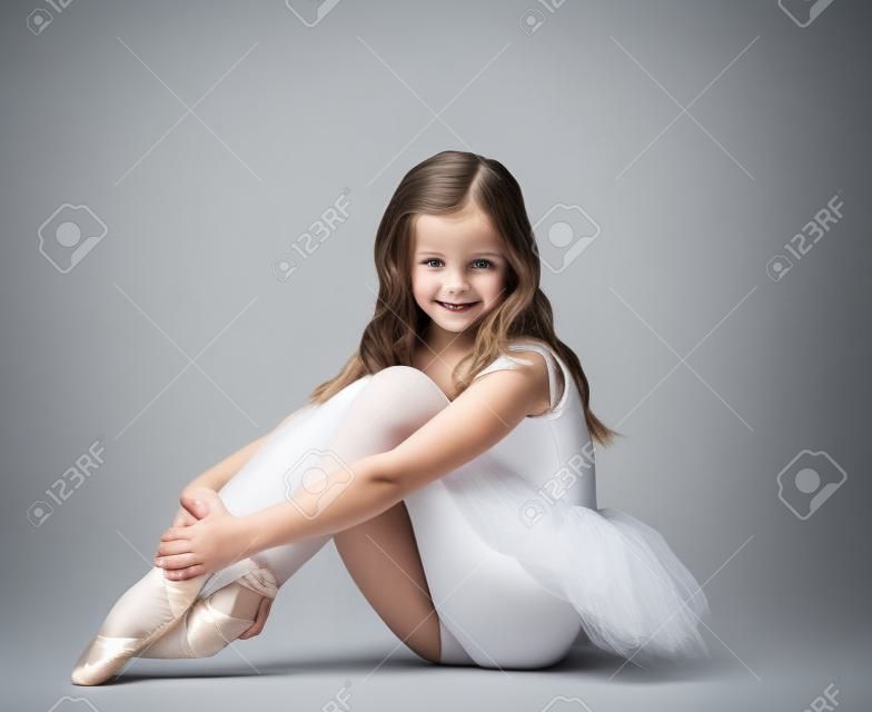 Schöne kleine Ballerina lächelnd in die Kamera, auf grauem Hintergrund