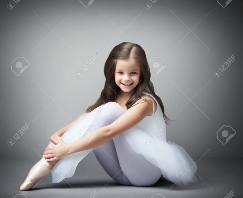 Schöne kleine Ballerina lächelnd in die Kamera, auf grauem Hintergrund