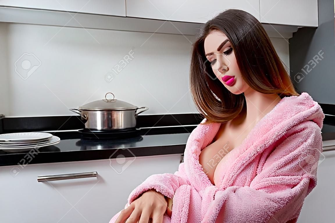 Imagen de chica guapa tetona posando en bata de baño de color rosa en la cocina