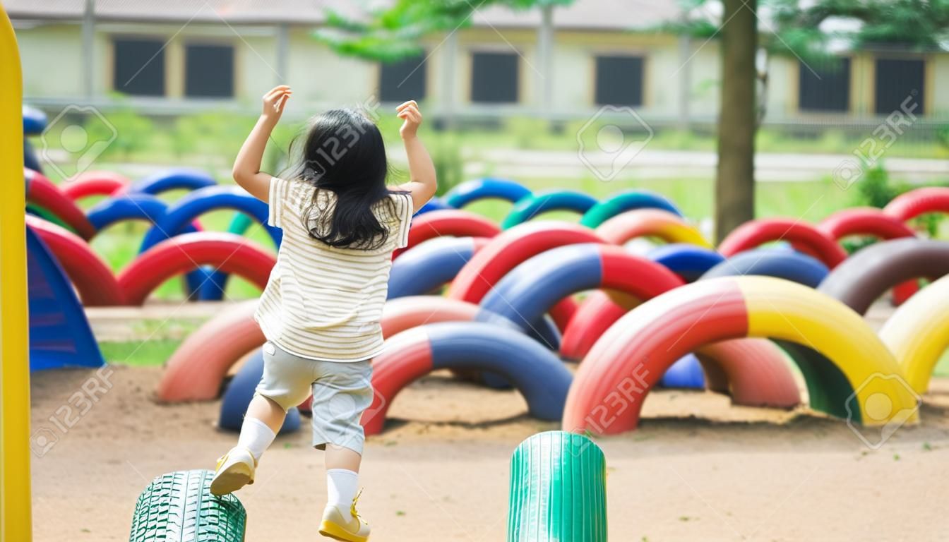 Une jolie fille asiatique sourit et joue dans la cour ou l'aire de jeux de l'école ou de la maternelle. activité estivale saine pour les enfants. petite fille asiatique grimpant à l'extérieur sur l'aire de jeux. enfant jouant sur une aire de jeux extérieure.
