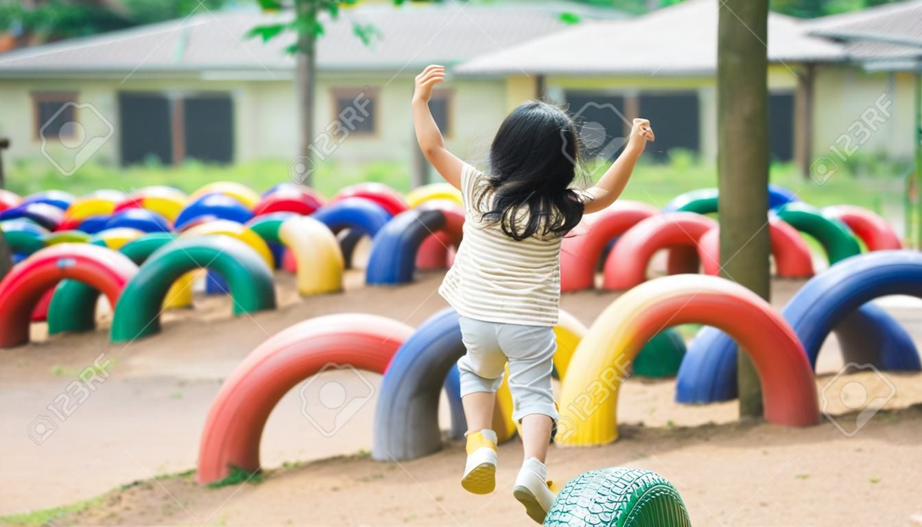 Une jolie fille asiatique sourit et joue dans la cour ou l'aire de jeux de l'école ou de la maternelle. activité estivale saine pour les enfants. petite fille asiatique grimpant à l'extérieur sur l'aire de jeux. enfant jouant sur une aire de jeux extérieure.