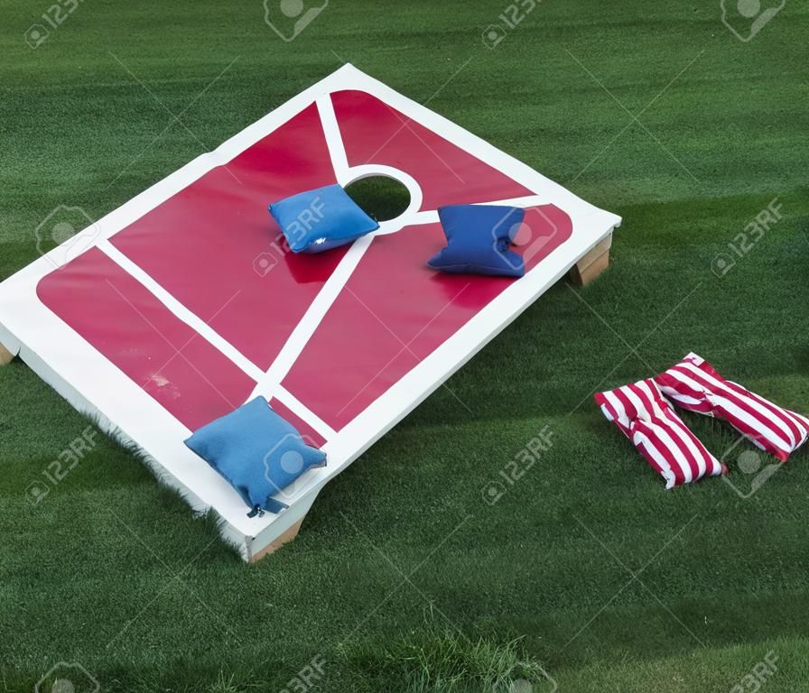 A cornhole board is set up with colorful beanbags resting on it after the competitiors have thrown them.