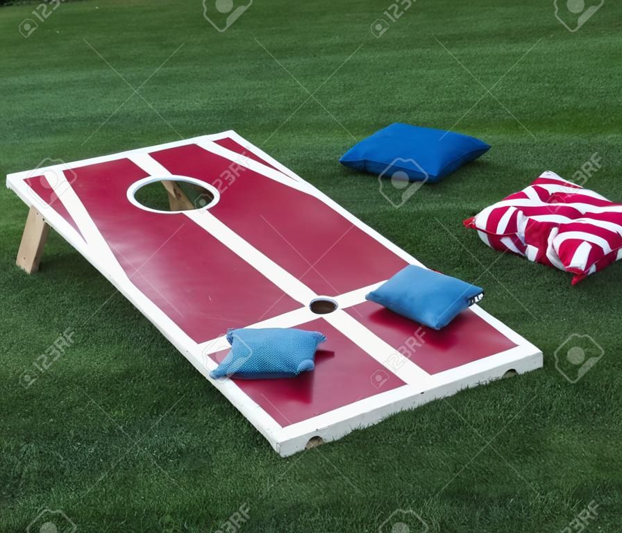 A cornhole board is set up with colorful beanbags resting on it after the competitiors have thrown them.