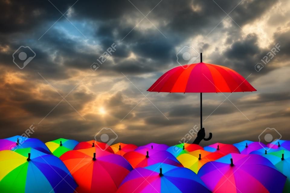 paraguas del arco iris en masa de paraguas negros, concepto que impulsan la creatividad o el liderazgo y diferente
