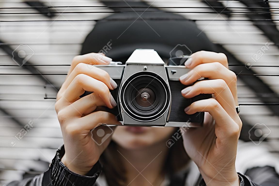 Colpo potato del turista con indifferenza vestito femminile con uno zaino che posa con la retro macchina fotografica della foto del film davanti alla parete dei graffiti. Concetto di viaggio e freelance.