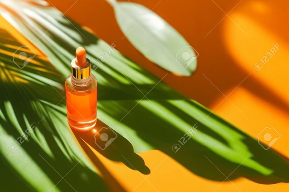 Natural sunshine and shadows from tropical plants. Orange background with daylight. Skincare products , natural cosmetic. Beauty concept for face and body care