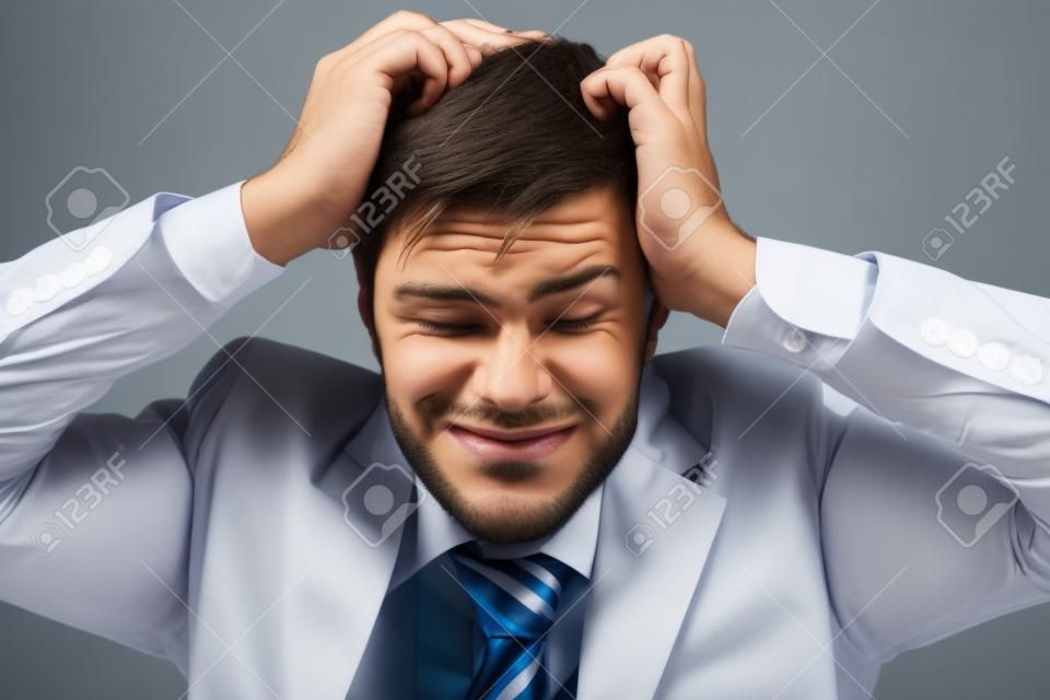 Frustrated young businessman pulling his hair, studio shot