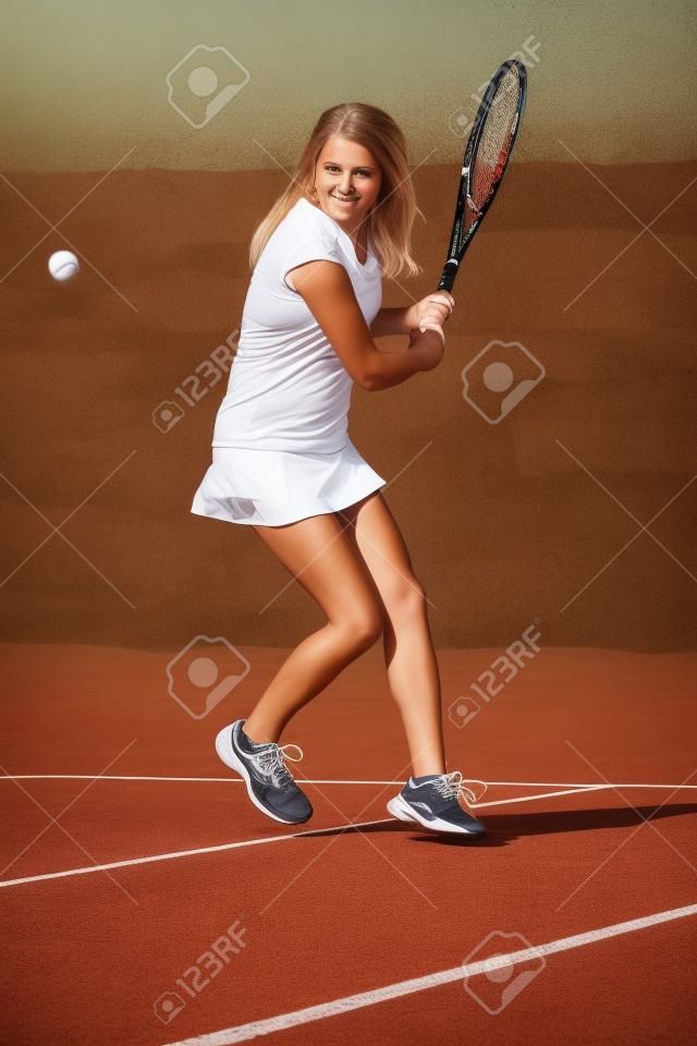 Portrait en pied d'une jeune femme jouant au tennis sur un terrain de scories