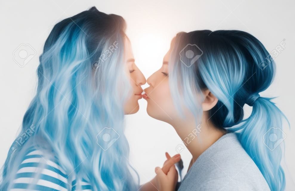 two girlfriends holding hands, hugging and kissing each other isolated over white background