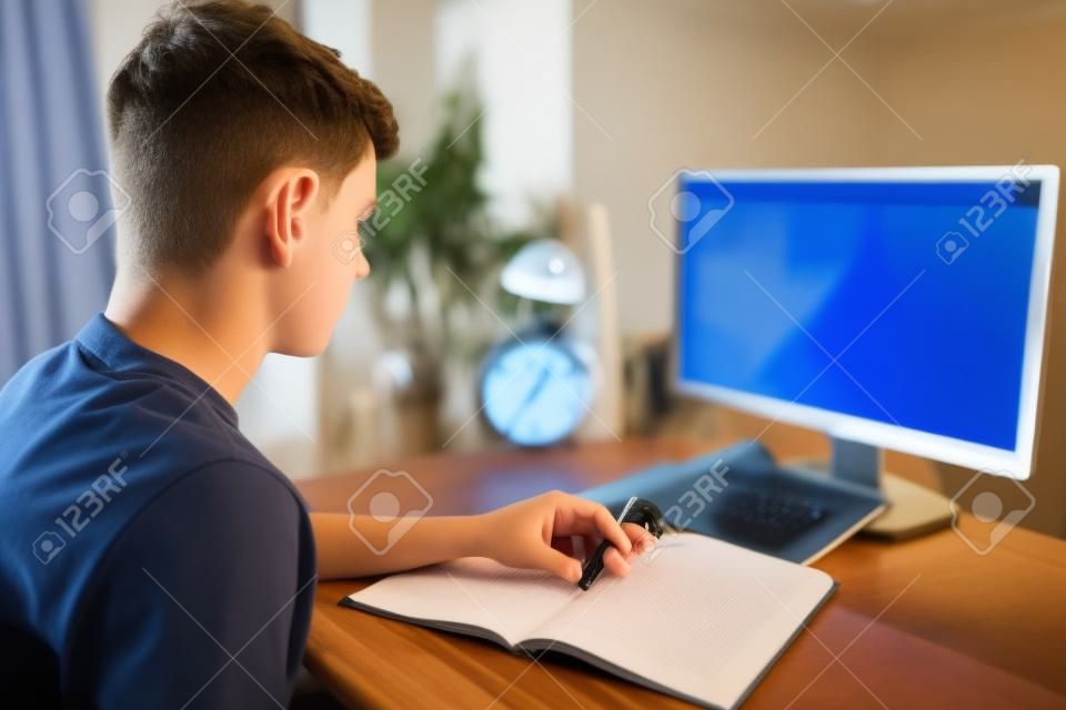 Teenage boy doing homework with the help of computer