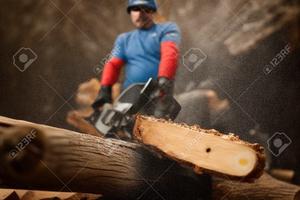 Close-up of a man sawing a log with a chainsaw