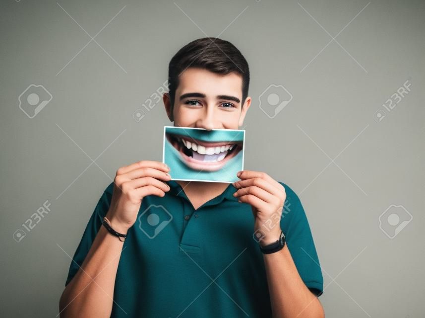 young man holding a picture of a mouth smiling