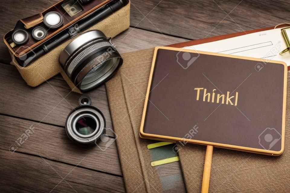 word THINK for educational concept image, personal planner book, vintage camera and wooden background