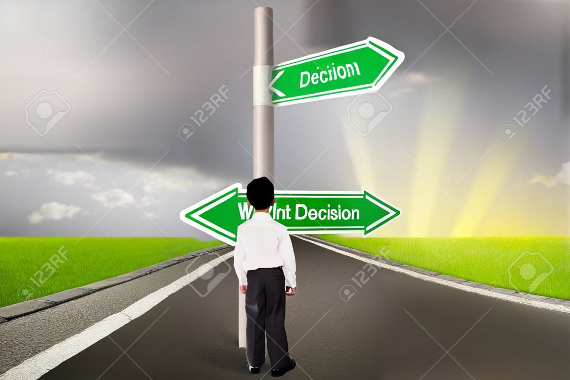 Pequeño niño de negocios está de pie en el camino con un signo de derecha vs decisión equivocada