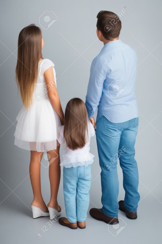 Lunghezza completa di famiglia in piedi in studio mentre guardando indietro, isolato su sfondo bianco