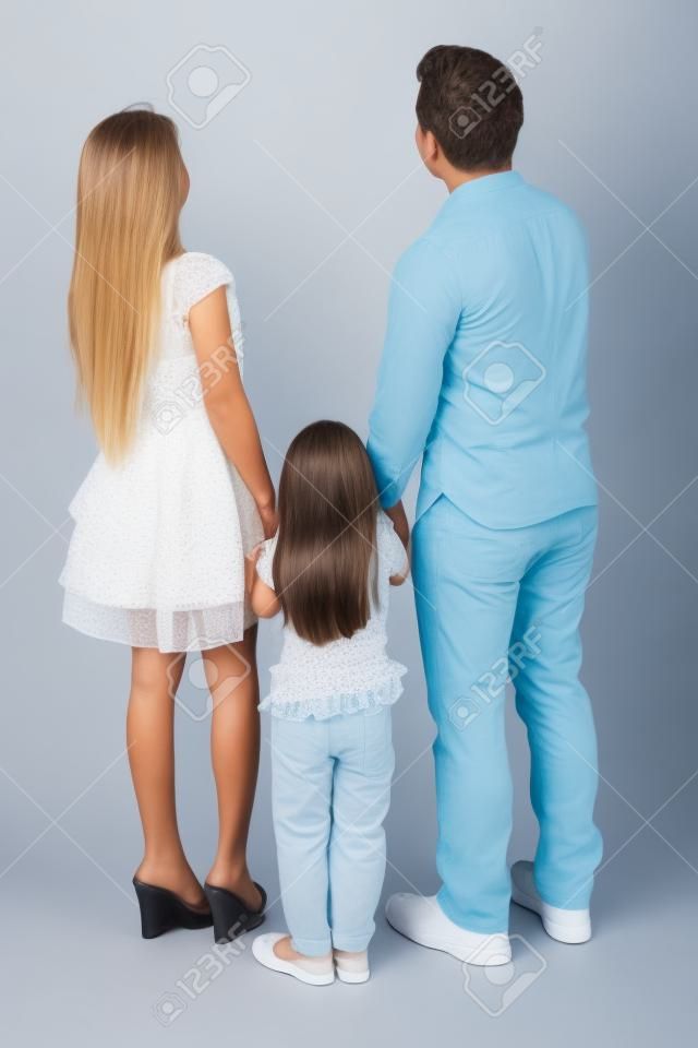 Lunghezza completa di famiglia in piedi in studio mentre guardando indietro, isolato su sfondo bianco