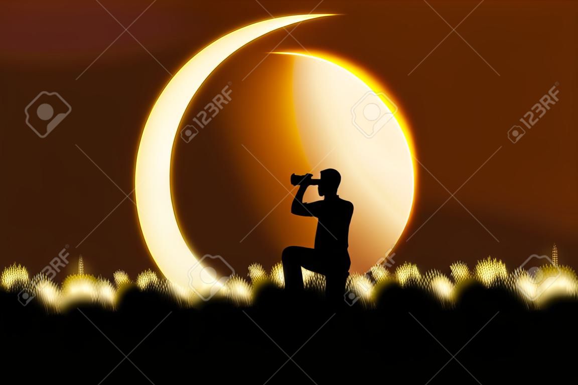 双眼鏡を使用して、日食を見ている若い男のシルエット