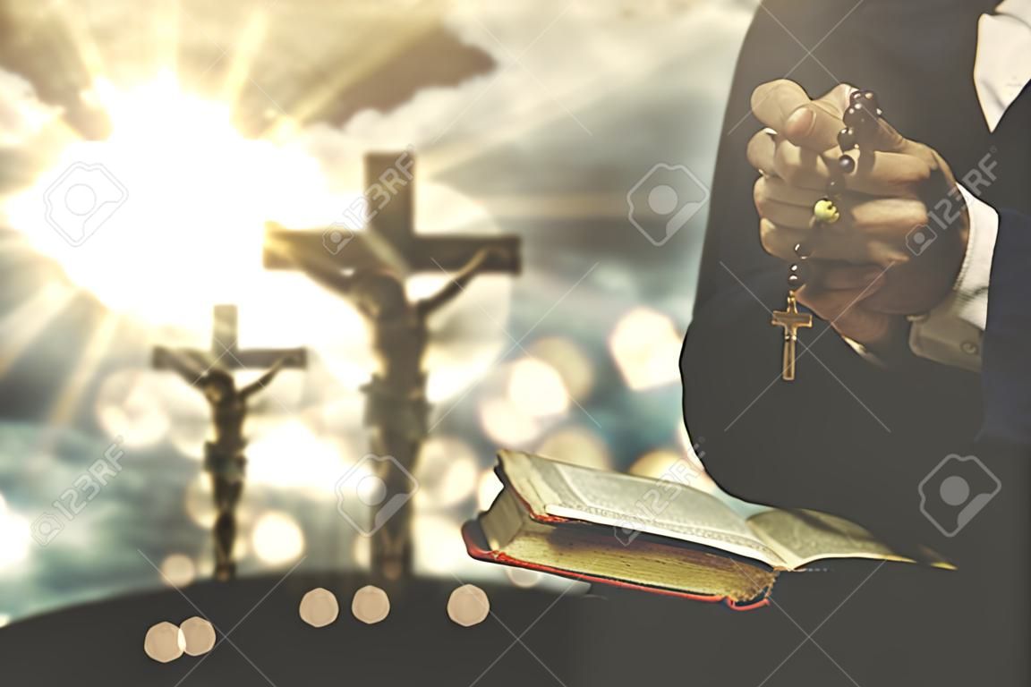 La persona cristiana che tiene una bibbia e un rosario con la crocifissione firmano sui precedenti