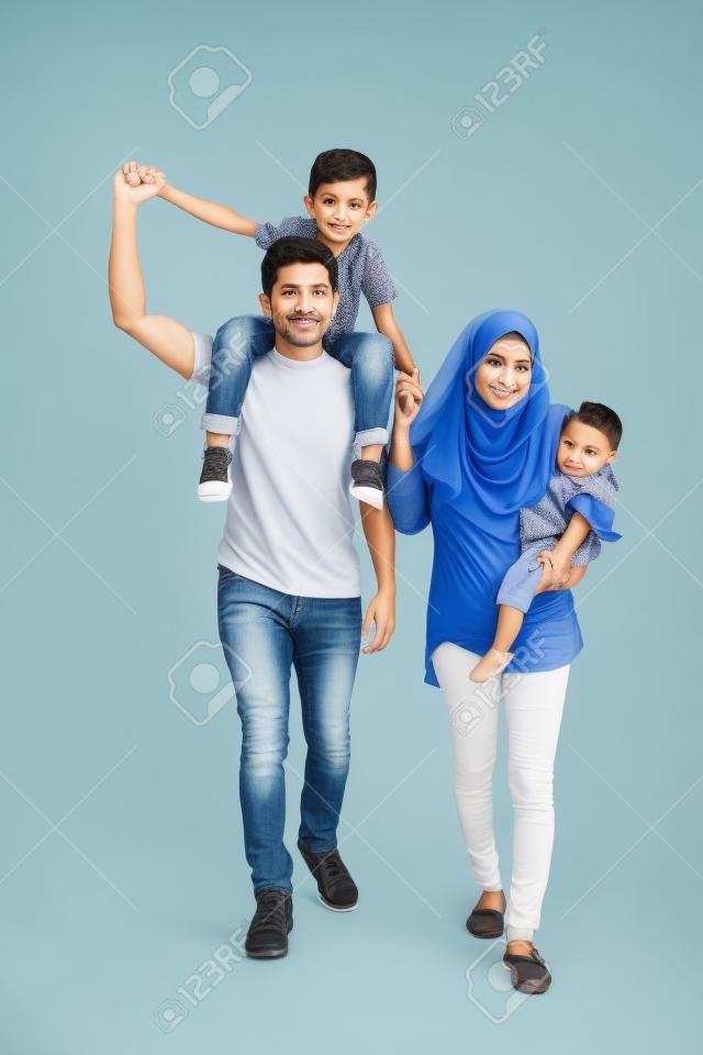 Volle lengte van moslim familie wandelen in de studio terwijl de vader draagt zijn zoon op schouder