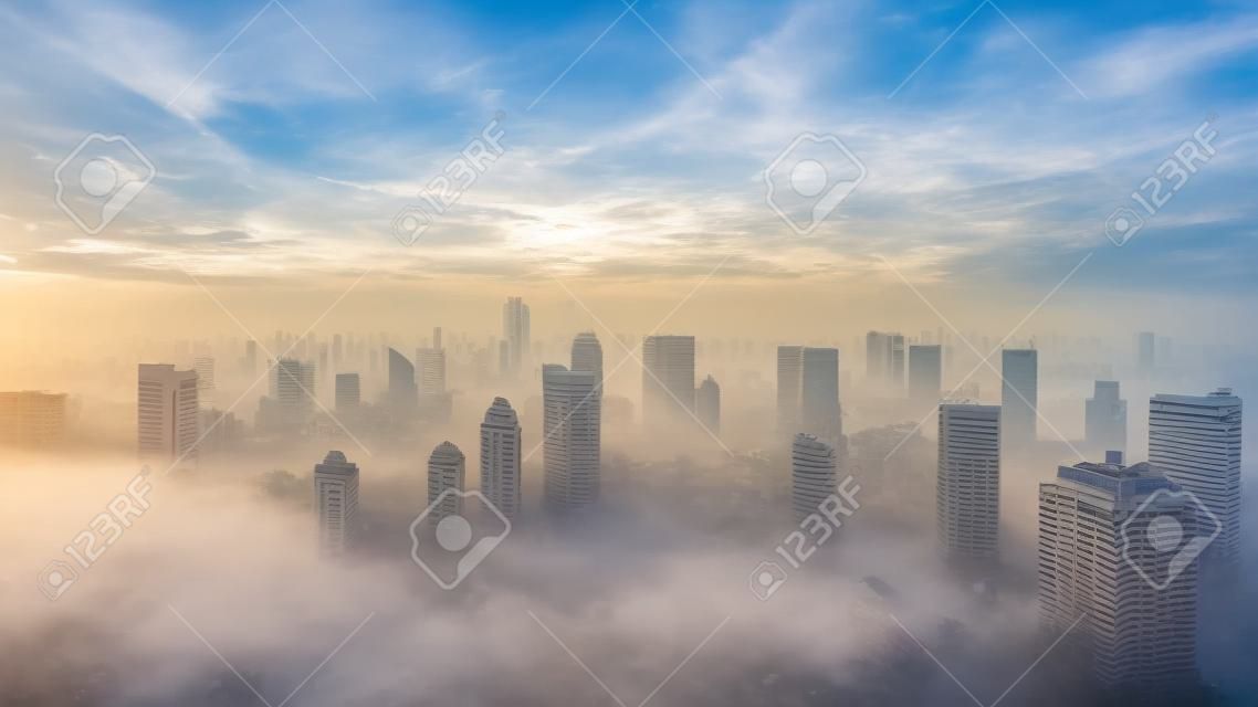 Aerial view of Jakarta skyline with skyscrapers and residential house at misty morning on sunrise time