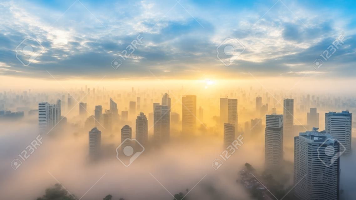 Aerial view of Jakarta skyline with skyscrapers and residential house at misty morning on sunrise time
