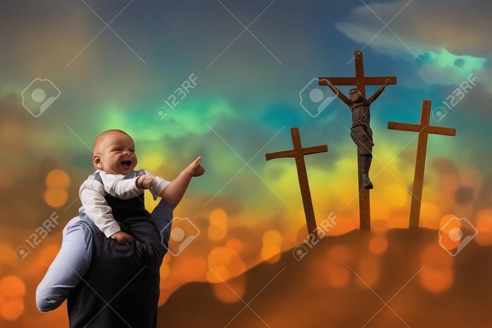 Image of father piggybacking his child while pointing at three crucifixes in the hill