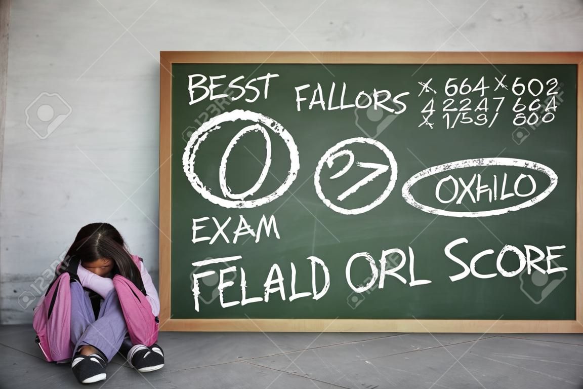 小さな女子高生のイメージは、黒板に彼女の失敗した試験のスコアと座っている間悲しそうに見えます