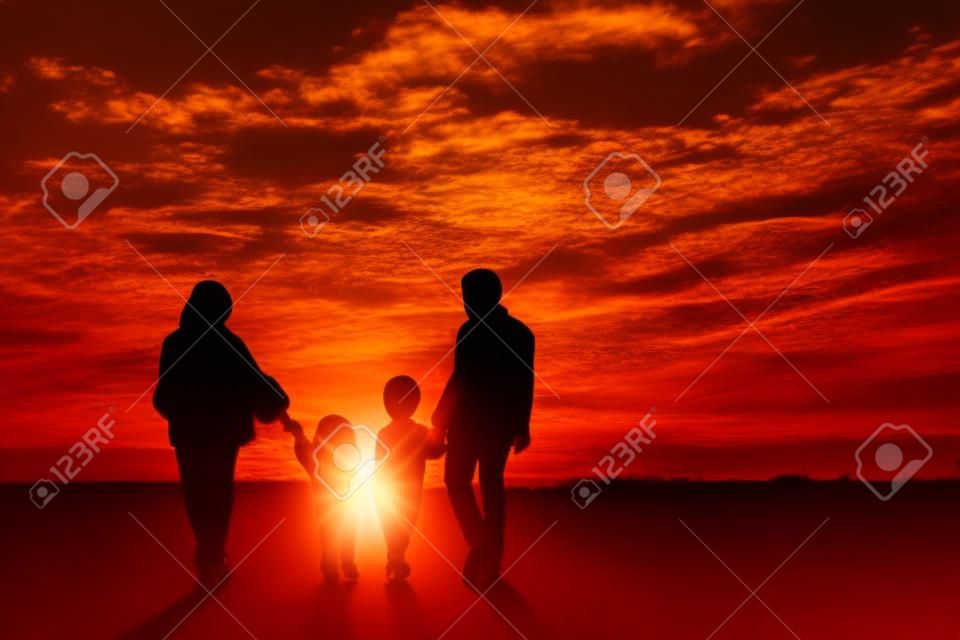 Silhouette of Muslim family holding hands together while walking toward city at sunrise time