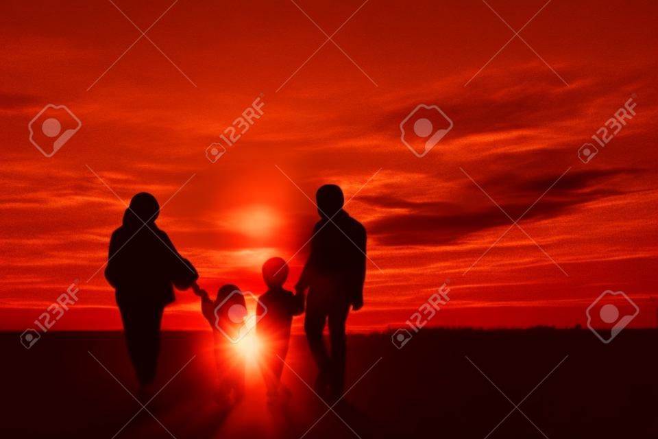 Silhouette of Muslim family holding hands together while walking toward city at sunrise time