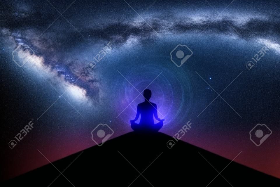 Silhouette of young woman doing yoga exercise on the mountain while meditating with milky way background. Shot in the metaverse