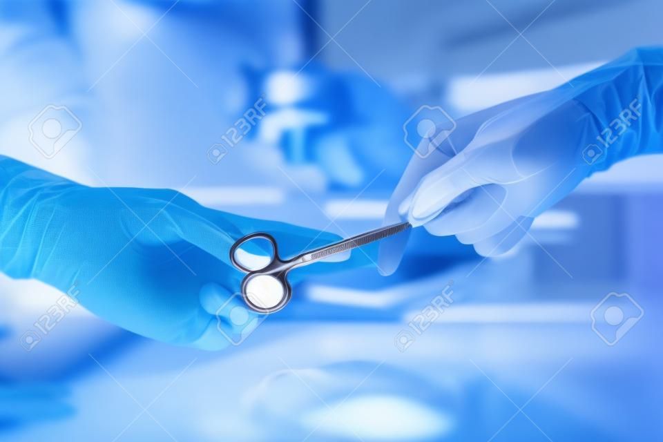 Gesundheitsversorgung und medizinische Konzept, Close-up von Chirurgen Hände halten chirurgische Scheren und Weitergabe chirurgische Geräte, Motion Blur Hintergrund.
