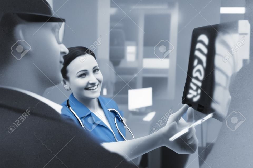Het is oké. Aangename vrouwelijke dokter die een radioscan wijst terwijl ze met haar collega praat.