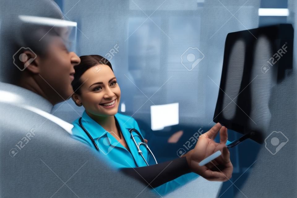 Het is oké. Aangename vrouwelijke dokter die een radioscan wijst terwijl ze met haar collega praat.