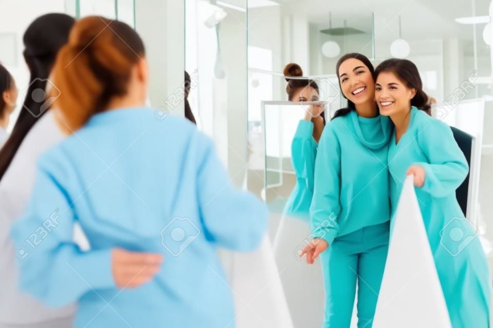 Nice delighted women standing together while looking into the mirror