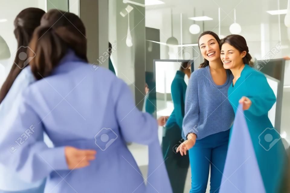 Nice delighted women standing together while looking into the mirror