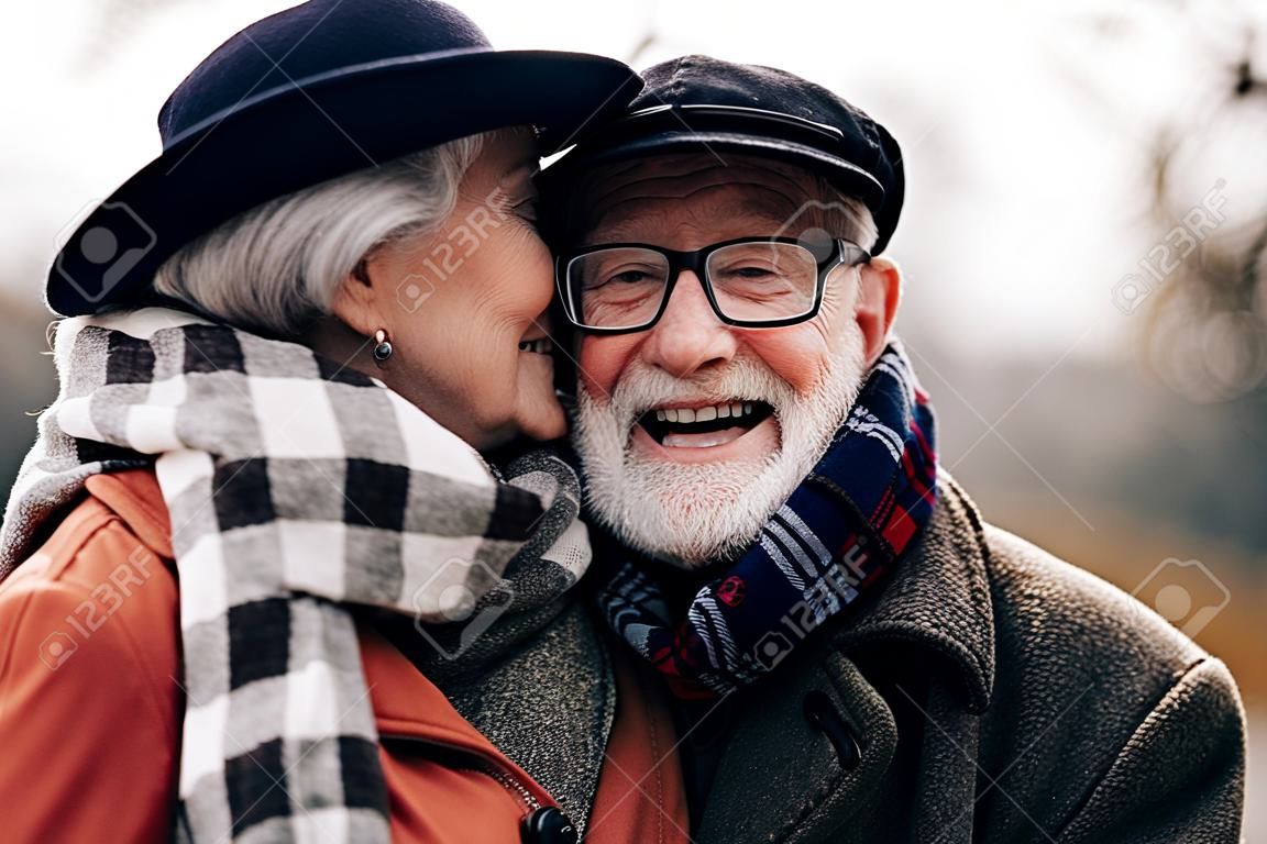 Elle est mignonne. Heureux retraité gardant le sourire sur son visage tout en embrassant sa femme