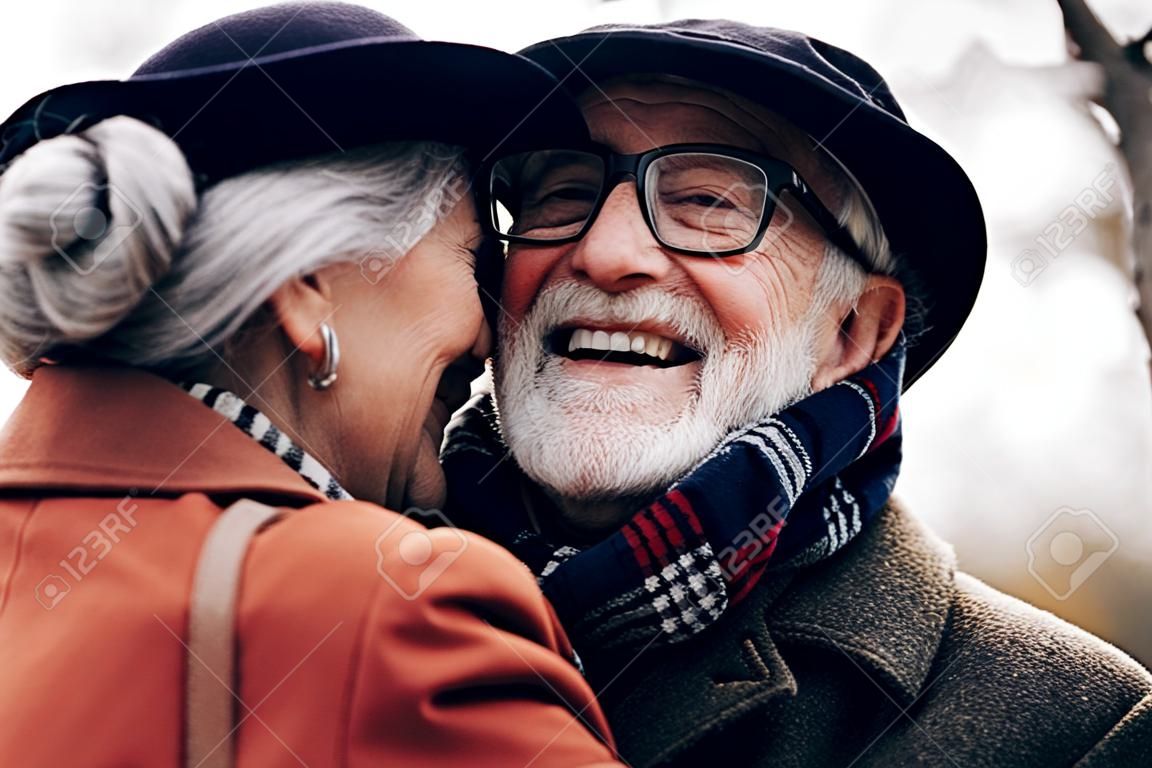 She is cute. Happy pensioner keeping smile on his face while embracing his wife