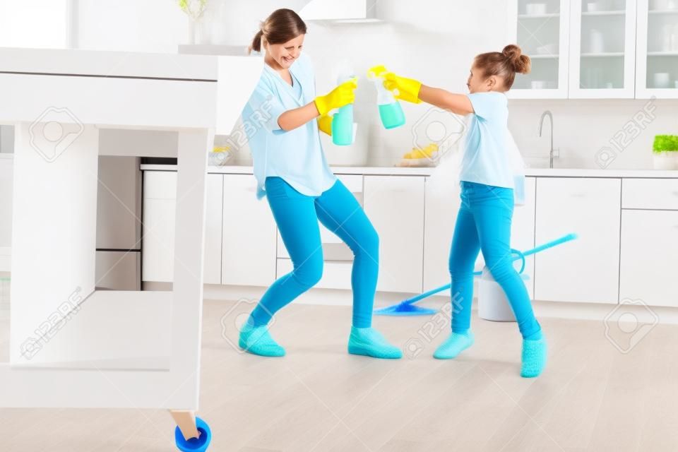 Reinigungsspray. Mutter und Tochter tragen Schutzhandschuhe und haben Spaß mit Reinigungsspray in der Küche