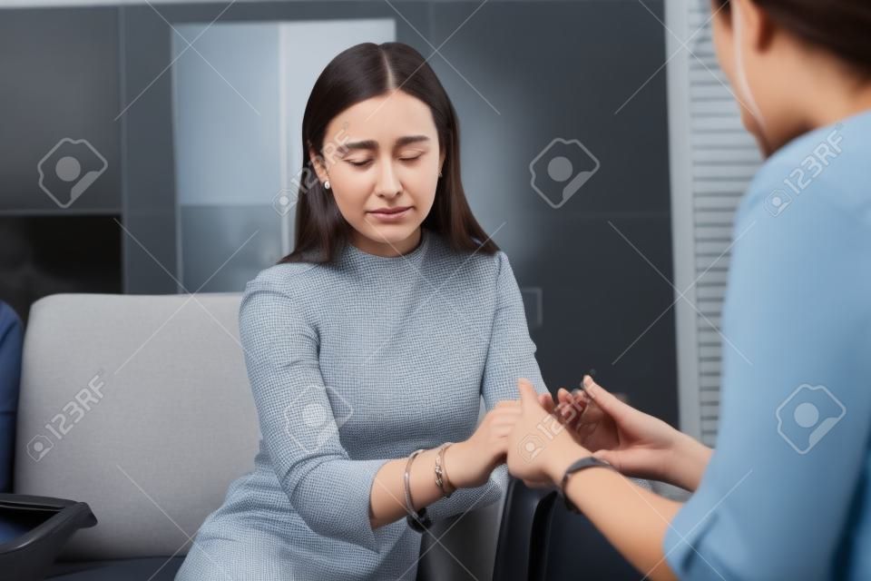Visiting a therapist. Upset crying scared attractive young long-haired lady being comforted by a therapist