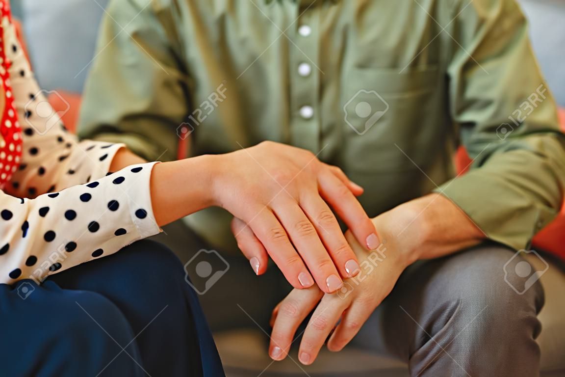 Cropped photo of a female psychoanalyst in a polka dot blouse consoling a male patient