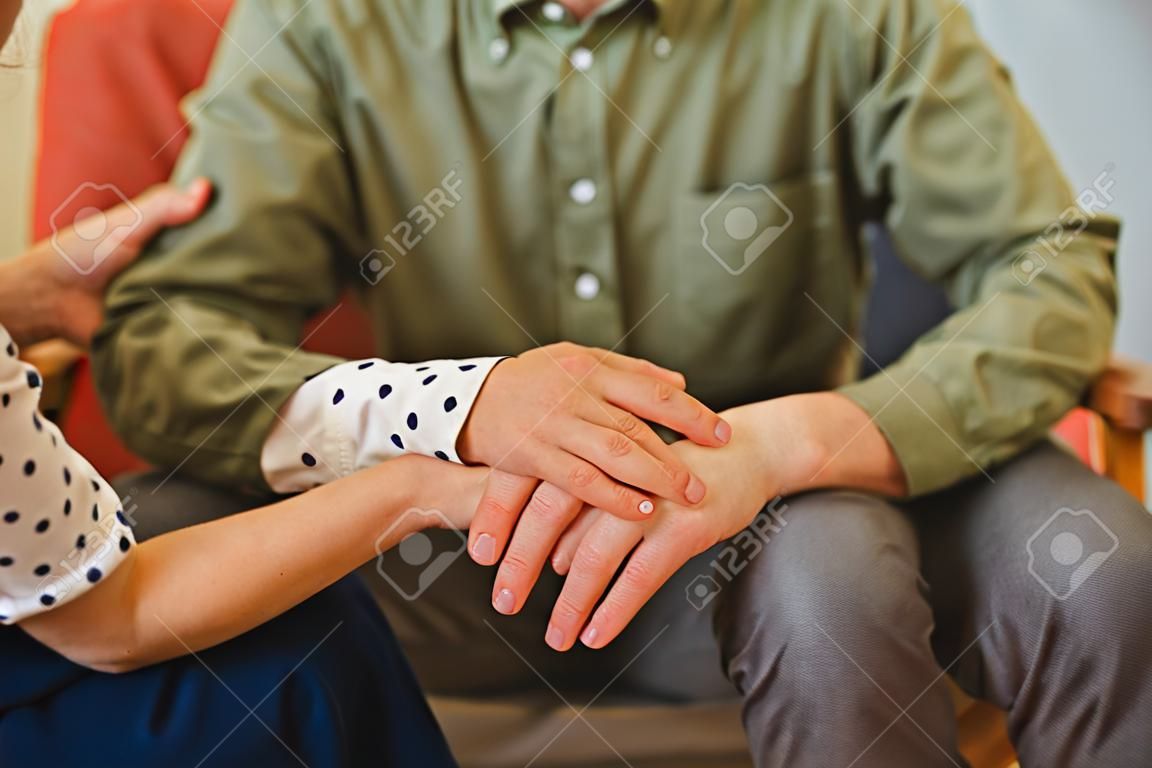 Cropped photo of a female psychoanalyst in a polka dot blouse consoling a male patient