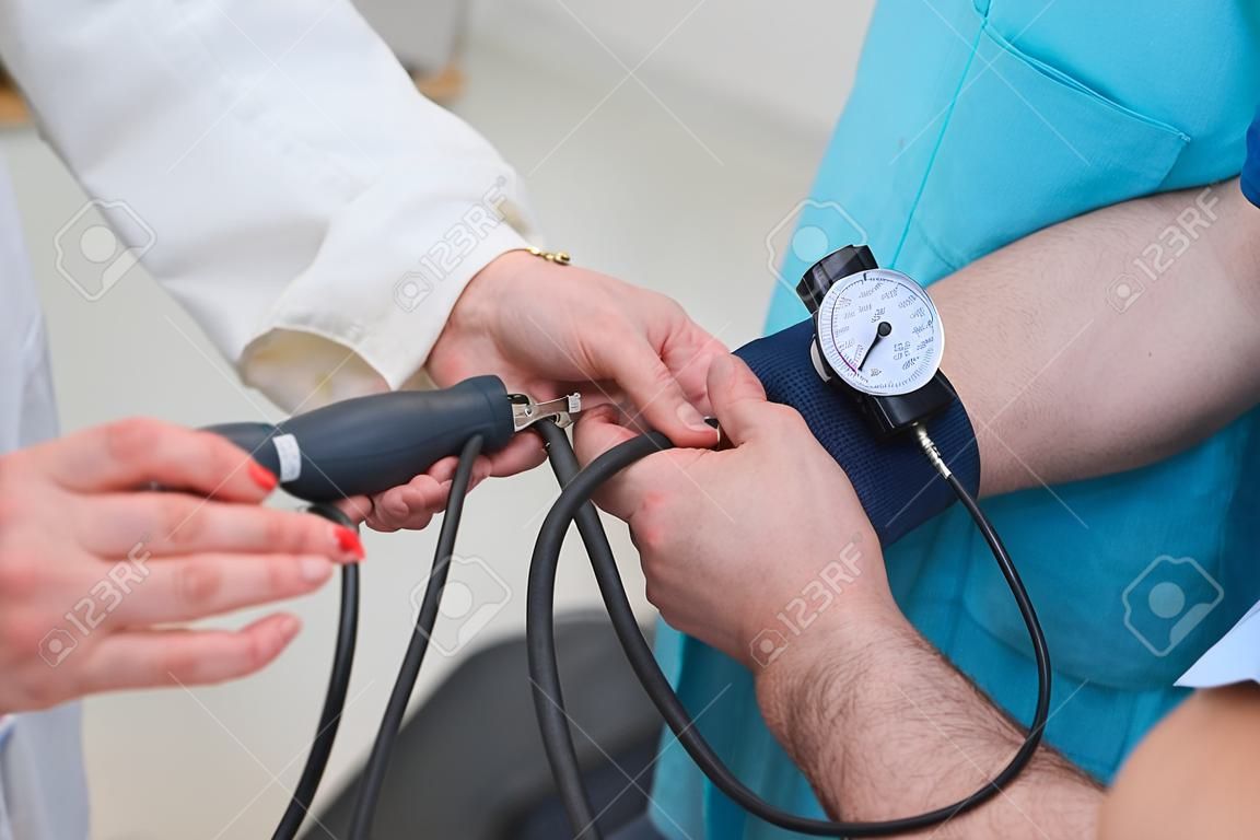 Foto recortada de un médico midiendo la presión arterial de un hombre en la clínica