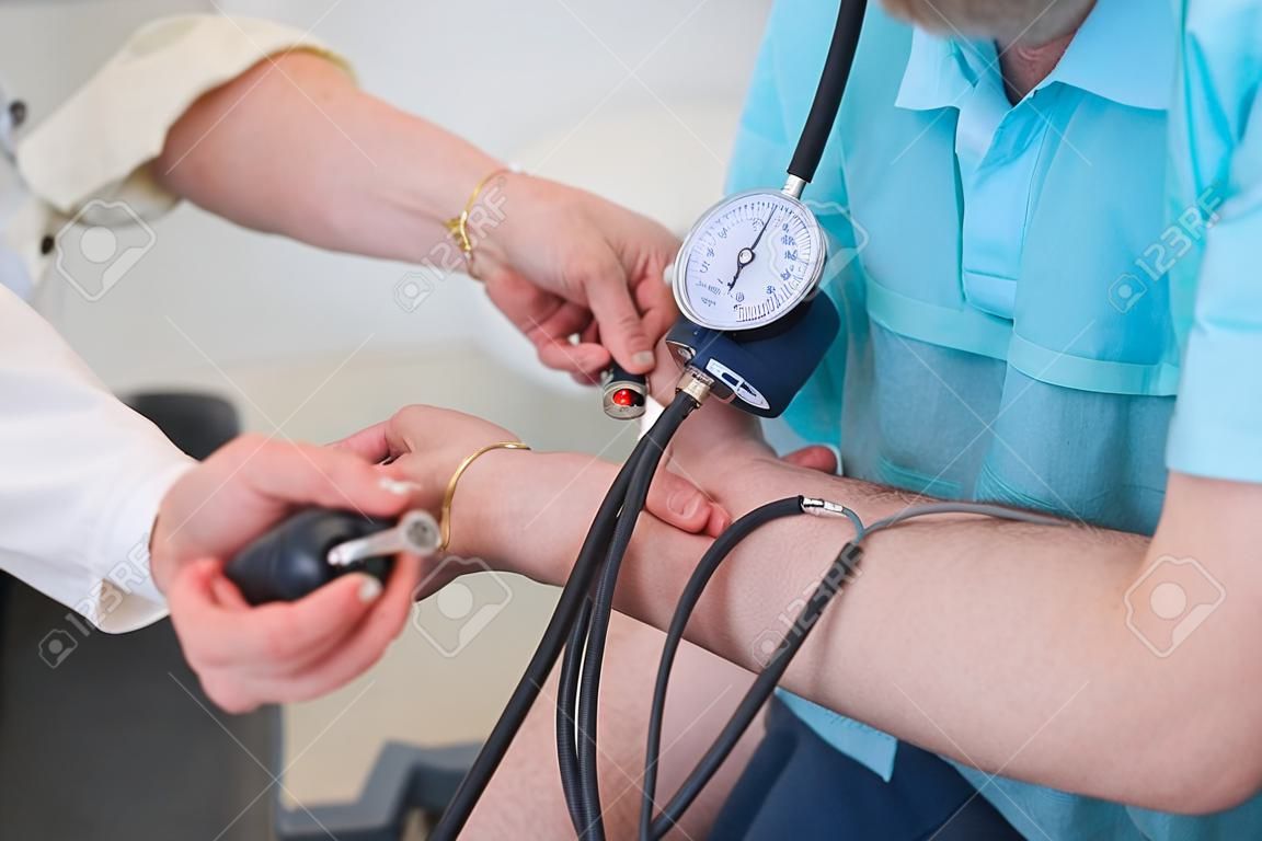 Foto recortada de un médico midiendo la presión arterial de un hombre en la clínica