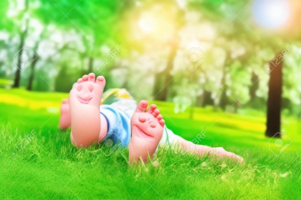 Child lying on green grass. Kid having fun outdoors in spring park. nature.