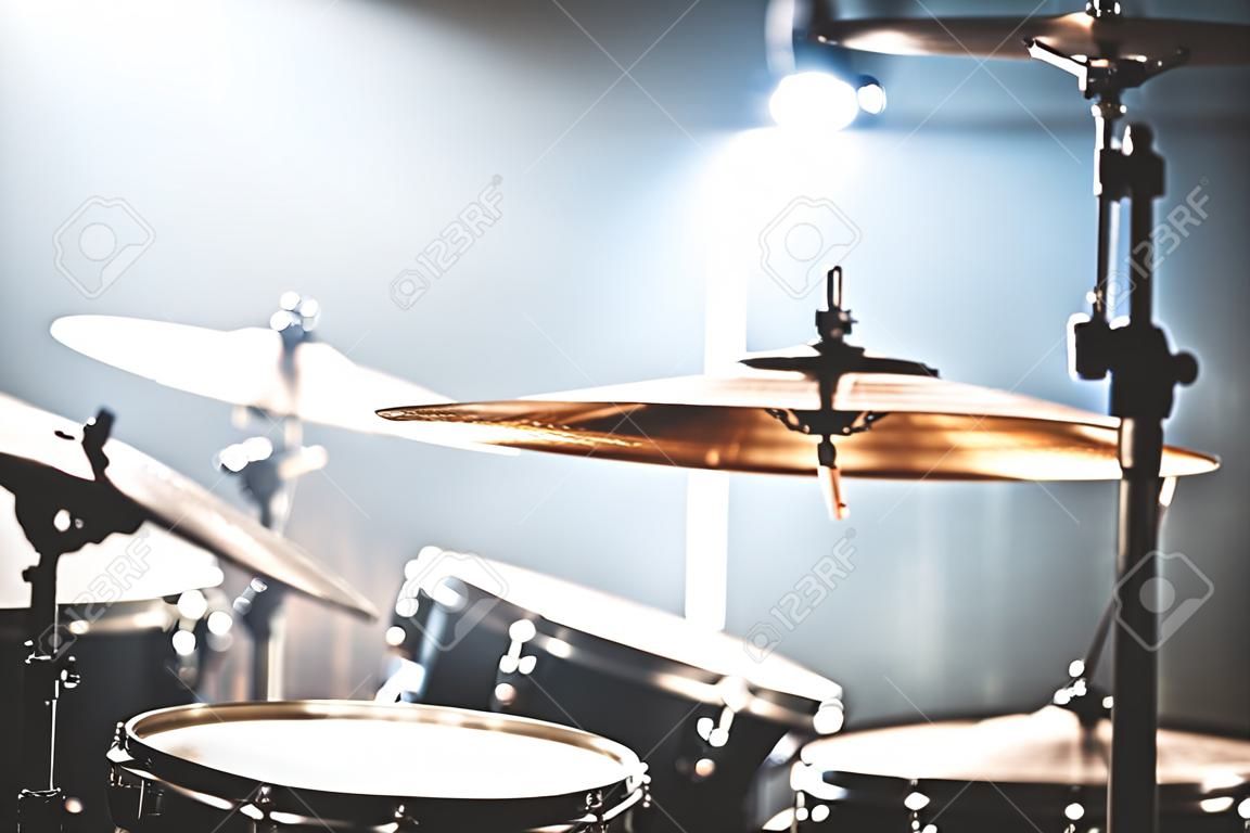 Close-up Drum set in a dark room against the backdrop of the spotlight. Atmospheric background symbol of playing rock or jazz drums. Copper plates on a cold background