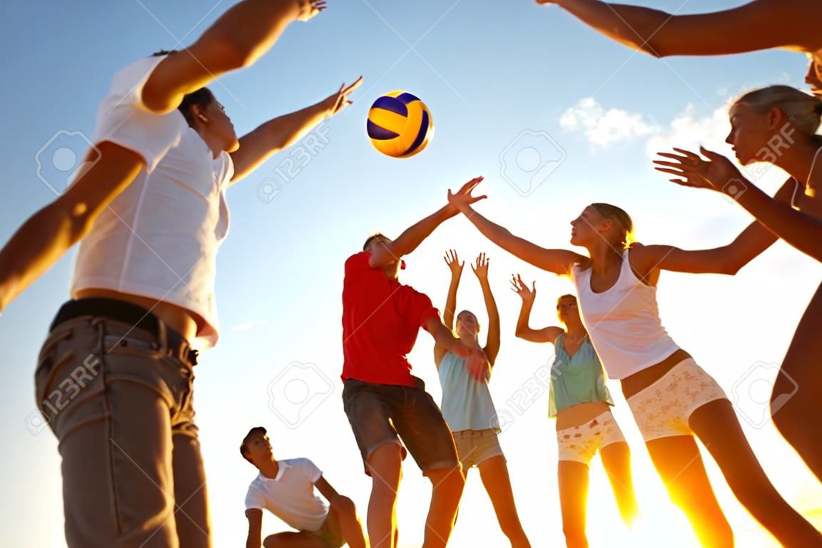 grupo de jóvenes jugando voleibol en la playa