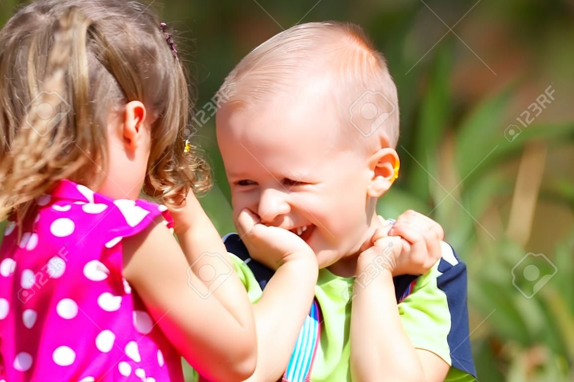 Two funny kids are playing, covering his face with his hands