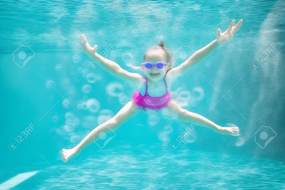 kleine meisje creëert bubbels onder water in het zwembad