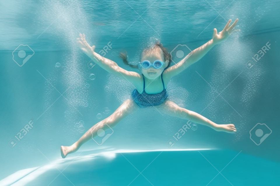 kleine meisje creëert bubbels onder water in het zwembad