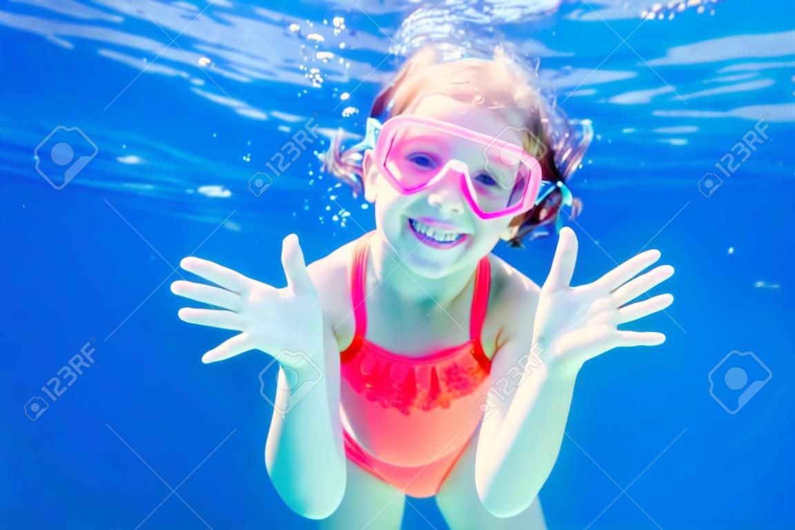 Cheerful little girl playing under  water in pool. Underwater photo.